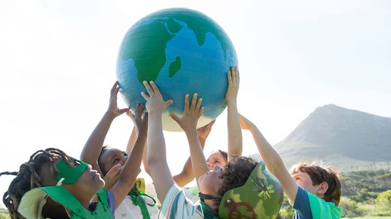 Des enfants qui portent une planéte terre en plastique.